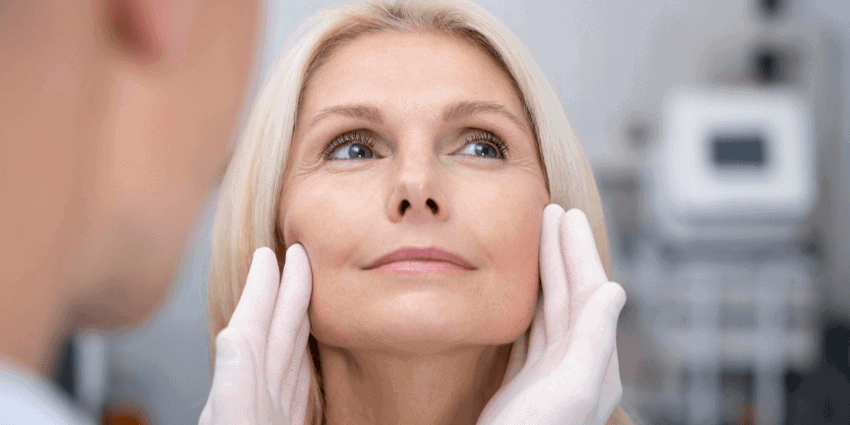 Mujer de 40 añosen consultorio, el doctro revisa su rostro para rejuvencimiento facial